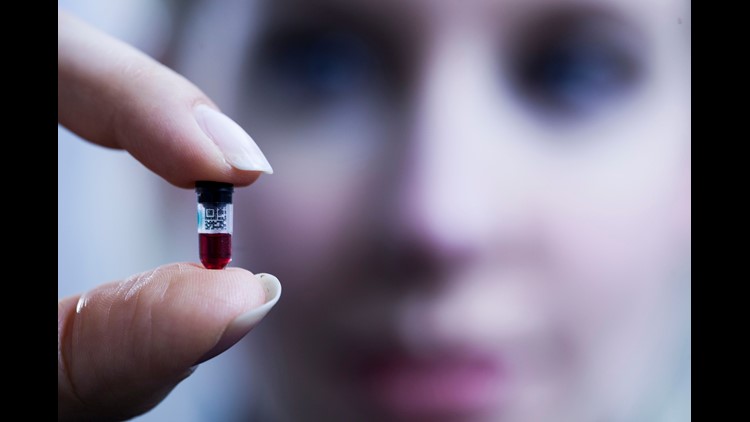 Theranos founder and CEO Elizabeth Holmes holds a nanotainer of blood at Theranos headquarters in Palo Alto Calif