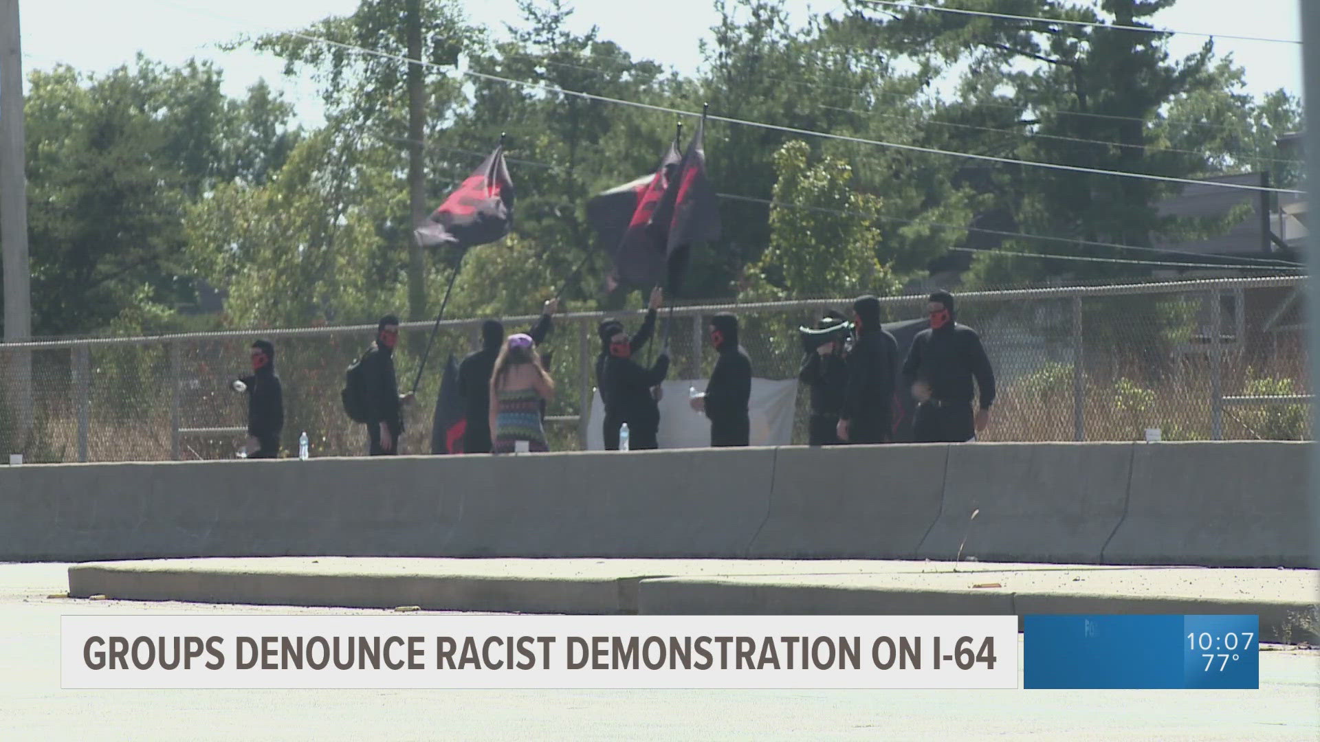 A group dressed in all black rallied on an Interstate 64 overpass, holding flags bearing Swastikas in red and black. Multiple groups decried the demonstration.