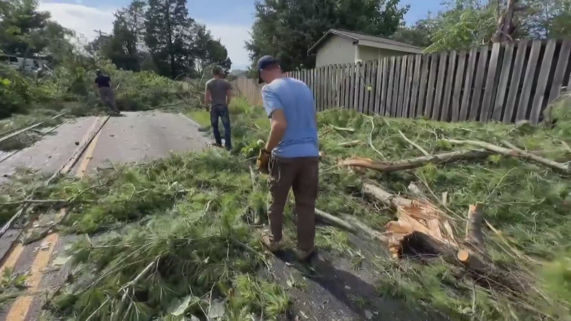 Chris Tucker, his kids and other neighbors are working together to clear trees and pick up debris.