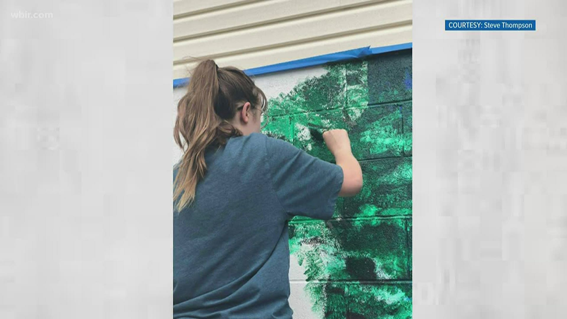 A high school senior who is creating a mural on the outside wall of a building along Maynardville Highway