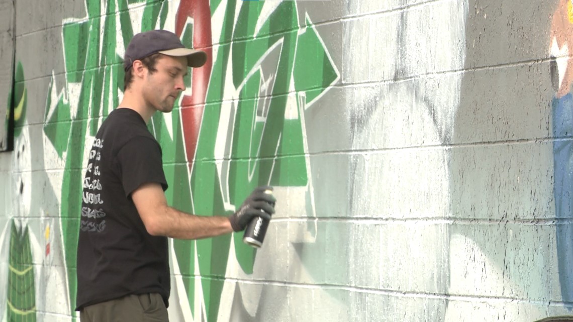 Artists paint over graffiti with scenes from classic holiday movies in