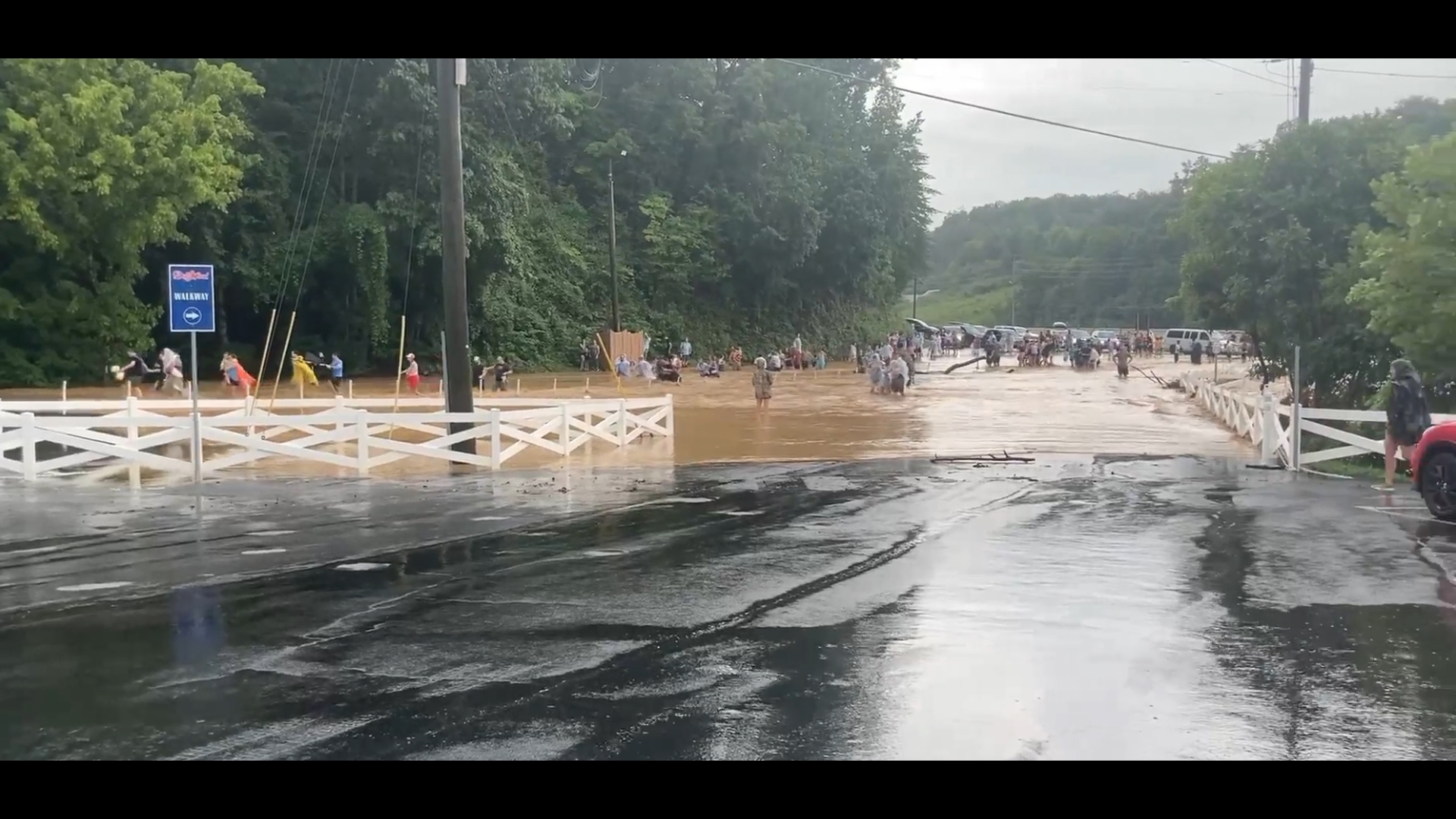 People wade through flooded Dollywood parking lot